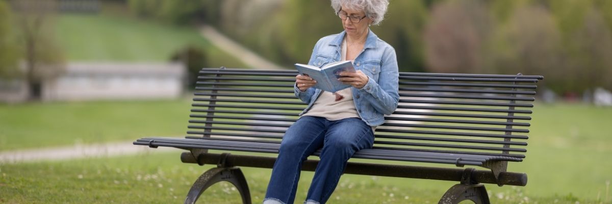 Frau auf Parkbank am Lesen