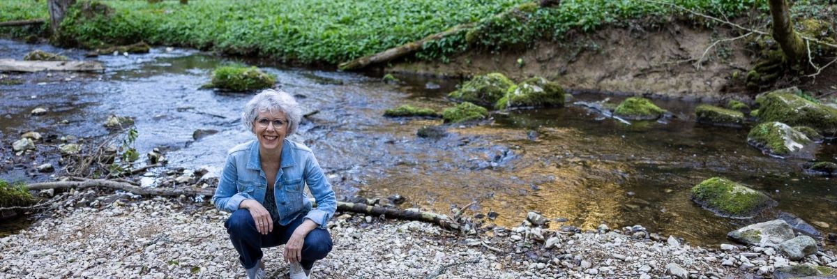 Frau am Bach kniehend